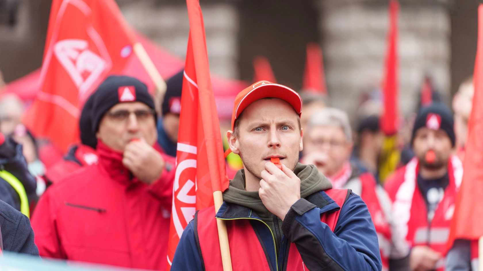 Ein junger Mann mit Trillerpfeife bei einem Warnstreik