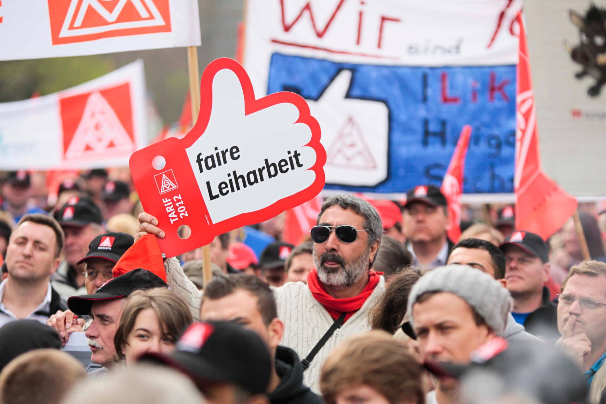 Ein Mann mit Sonnenbrille hält bei einer Demonstration ein Schild mit der Aufschrift: Faire Leiharbeit